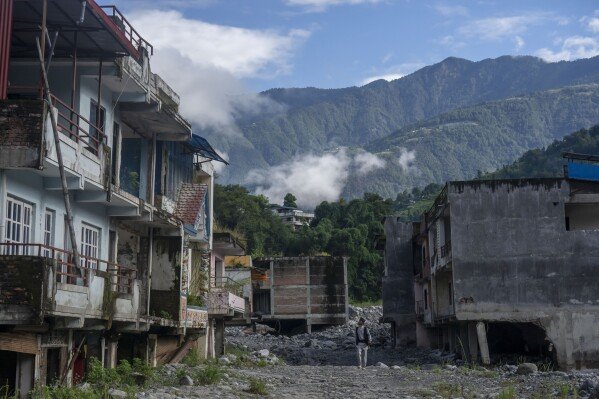 A man walks by abandoned houses in Chanaute Market, Melamchi, northeast of Kathmandu, Nepal, Sunday, Sept. 15, 2024, damaged by floods in 2021. (AP Photo/Niranjan Shrestha)