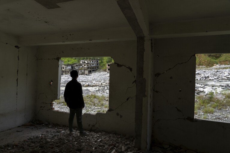 A man gazes out from an abandoned house in Chanaute Market, Melamchi, northeast of Kathmandu, Nepal, on Sunday, Sept. 15, 2024, damaged by floods in 2021. (AP Photo/Niranjan Shrestha)