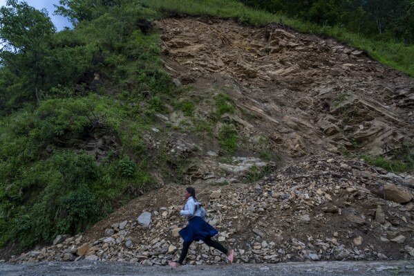 A girl runs in front of the recent landslide at Gyalthum, Melamchi, northeast of Kathmandu, Nepal, Sunday, Sept. 15, 2024. (AP Photo/Niranjan Shrestha)