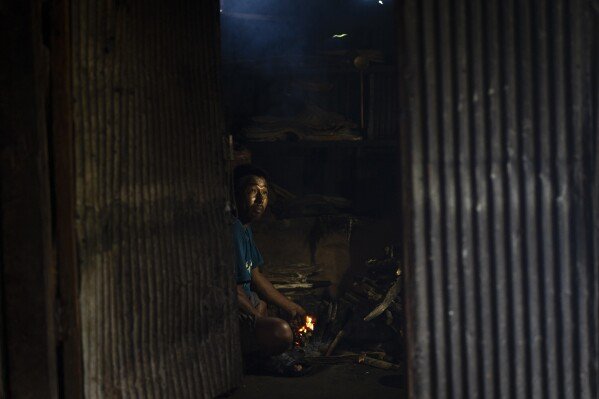 Sukuram Tamang, 50, prepares to cook food inside a temporary shelter on rented land in Melamchi, northeast of Kathmandu, Nepal, on Saturday, Sept. 14, 2024, after he lost his home in a landslide. (AP Photo/Niranjan Shrestha)