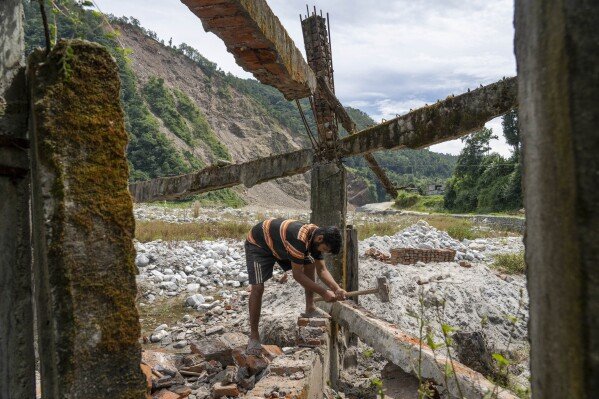 Saroj Lamichane salvages bricks from the ruins of his house northeast of Kathmandu, Nepal, Saturday, Sept. 14, 2024, that was destroyed by floods in 2021. (AP Photo/Niranjan Shrestha)