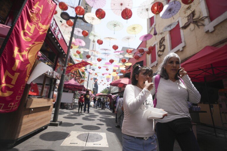 Tourists walk under colorful umbrellas and lanterns at Chinatown in Mexico City's historic center, Saturday, June 8, 2024. (AP Photo/Fernando Llano)