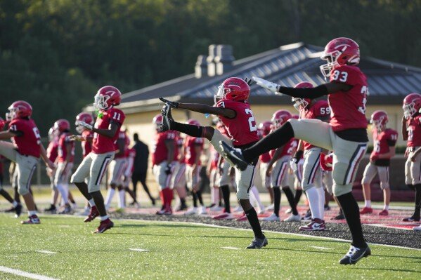 Members of the Brandon High freshman football team warm up before a game against Clinton High in Brandon, Miss., Tuesday, Aug. 27, 2024. (AP Photo/Gerald Herbert)