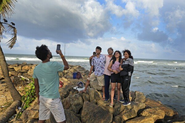 Indian tourists pose for a photograph on a beach in Colombo, Sri Lanka, Tuesday, Sept. 17, 2024. (AP Photo/Rajesh Kumar Singh)