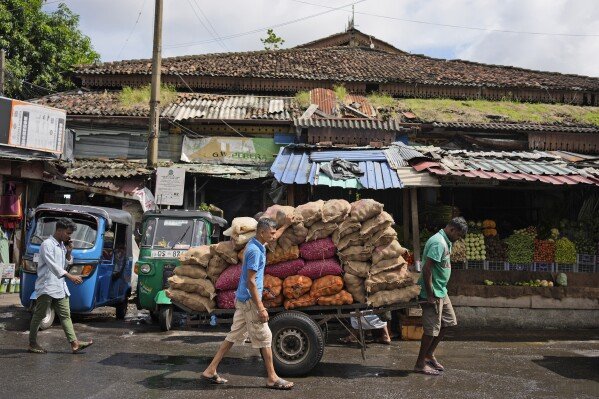 Workers pull a hand cart loaded with sacks of vegetables through a wholesale market in Colombo, Sri Lanka, Friday, Sept. 13, 2024. (AP Photo/Eranga Jayawardena)