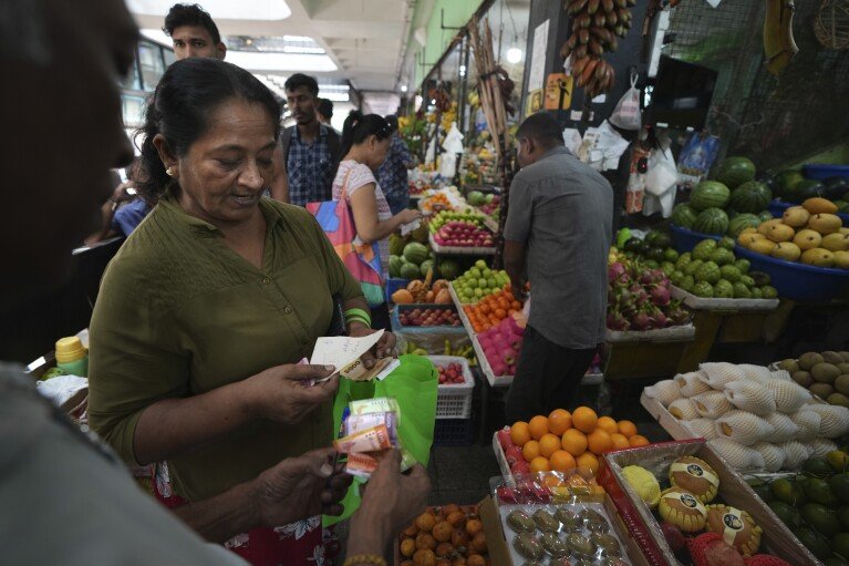 A woman buys fruits from a stall at a local wholesale market, in Colombo, Sri Lanka, Wednesday, Sept. 18, 2024. (AP Photo/Rajesh Kumar Singh)