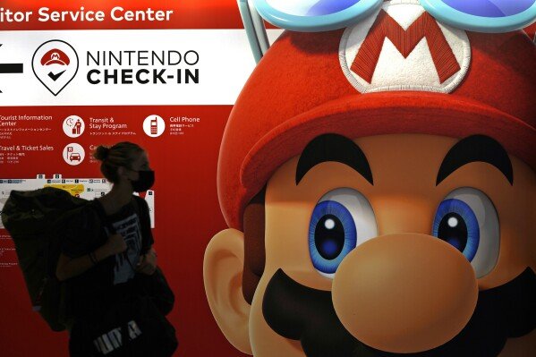 FILE - A traveler walks past an advertisement featuring a Nintendo character at Narita airport in Narita near Tokyo, on June 10, 2022. (AP Photo/Shuji Kajiyama, File)