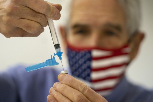 Dr. Sydney Sewall fills a syringe with the COVID-19 vaccine at the Augusta Armory, Dec. 21, 2021, in Augusta, Maine. (AP Photo/Robert F. Bukaty, File)