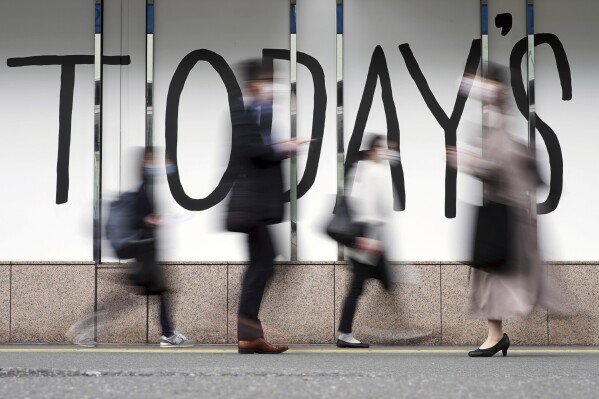 People wearing face masks walk along a street April 7, 2022, in Tokyo. (AP Photo/Eugene Hoshiko, File)