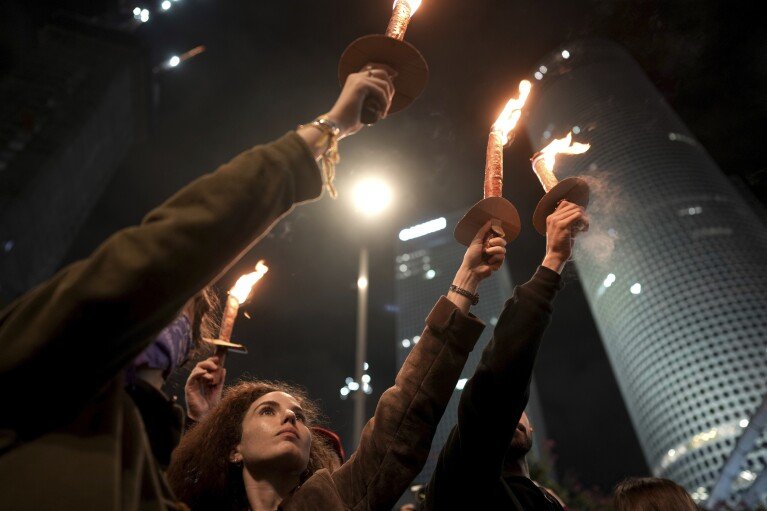 Demonstrators hold torches as they gather during a protest calling for the release of all hostages held captive by Hamas in the Gaza Strip, in Tel Aviv, Israel on Saturday, Jan. 18, 2025. (AP Photo/Oded Balilty)