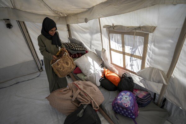 Majida Abu Jarad packs belongings as she prepares to go back to the family's home in the north, at a camp for displaced Palestinians in the Muwasi area, southern Gaza Strip, Saturday, Jan. 18, 2025. (AP Photo/Abdel Kareem Hana)
