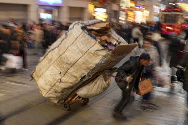 A man pulls his cart with plastic bottles and discarded cartons at main Istiklal street in Istanbul, Turkey, Wednesday, Jan. 29, 2025. (AP Photo/Francisco Seco)
