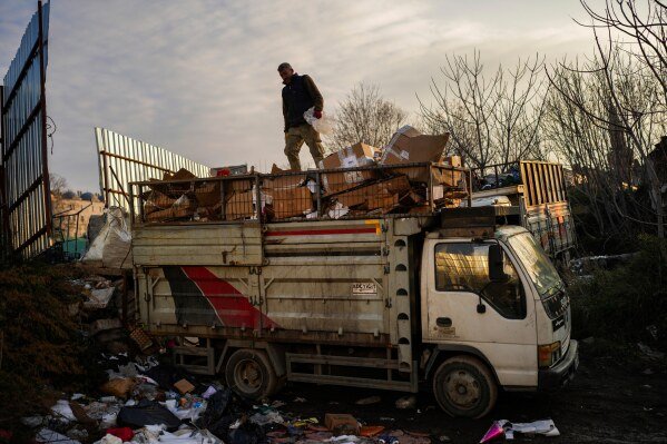 Hikmet Kilic loads a lorry with discarded cartons in Istanbul, Turkey, Tuesday, Feb. 26, 2025. (AP Photo/Francisco Seco)