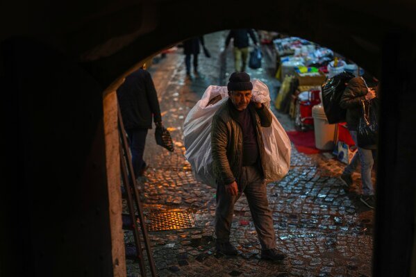 A man carries a sack with discarded cartons at Eminonu commercial area in Istanbul, Turkey, Wednesday, Feb. 5, 2025. (AP Photo/Francisco Seco)
