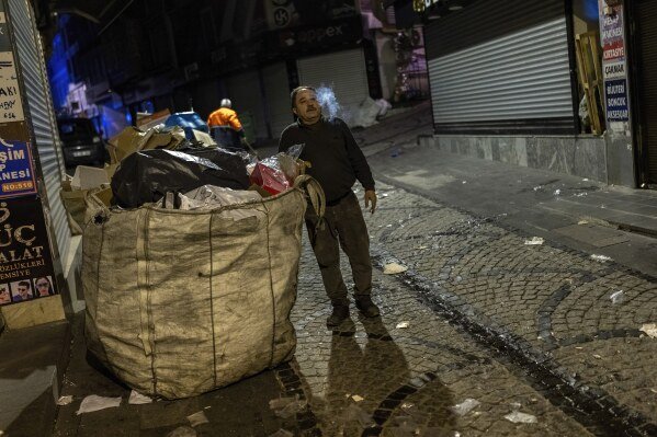 Veysel Dogan smokes a cigarette as he and his sons load a lorry with discarded cartons at Eminonu commercial area in Istanbul, Turkey, Tuesday, Feb. 26, 2025. (AP Photo/Francisco Seco)