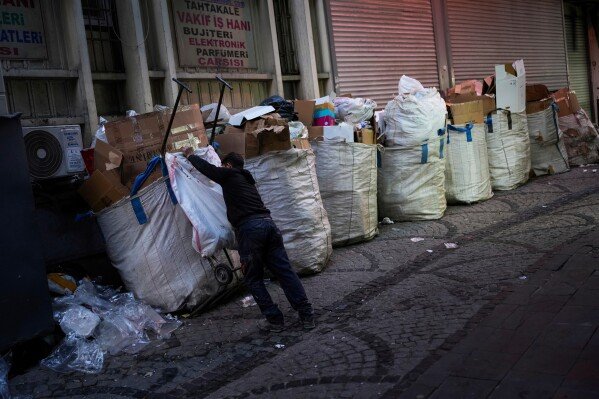 Ergin Dogan, 29, gather sacks full of discarded carton and papers at Eminonu commercial district in Istanbul, Turkey, Tuesday, Feb. 26, 2025. (AP Photo/Francisco Seco)
