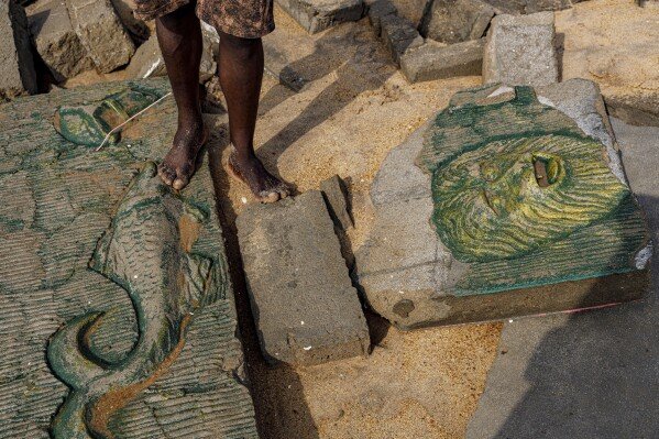 Dennis Dostey Dorve stands by a sculpture design on a collapsed wall of his late father's room, which was destroyed by coastal erosion in Avegadzi, Ghana, Wednesday, March 5, 2025 (AP Photo/Misper Apawu)