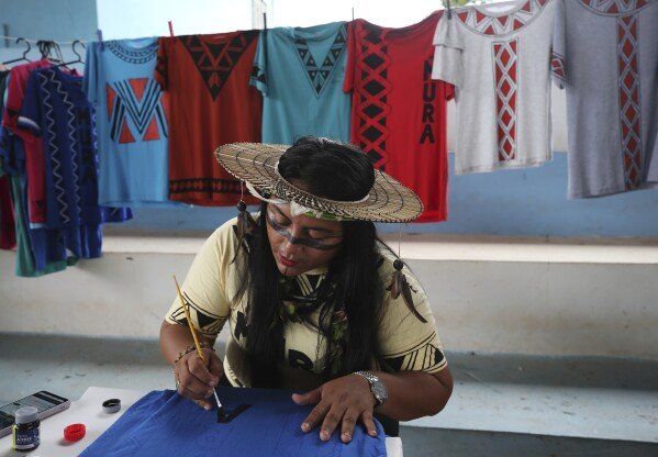 Jeicy Mura paints shirts with Indigenous themes during a gathering of the Mura Indigenous community in Autazes, Amazonas state, Brazil, Wednesday, Feb. 19, 2025. (AP Photo/Edmar Barros)